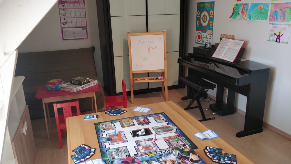 Salle de jeux avec un piano, un lit double BZ et plein de jeux de société